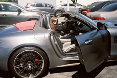 a woman sitting in the driver's seat of a sports car