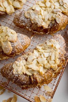 several pastries are cooling on a rack with powdered sugar and almond toppings