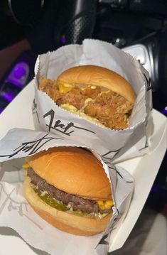 two large hamburgers sitting next to each other on top of a white paper tray