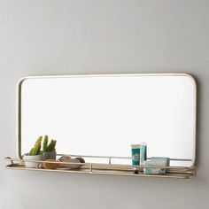 there is a mirror on the wall with some items in front of it and a plant next to it