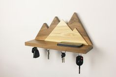 a wooden shelf with key hooks and mountains on it