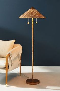 a floor lamp sitting next to a chair in front of a dark blue wall and white carpet