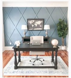 a desk with a laptop and lamp on it in front of a blue accent wall