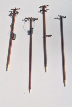 four different types of metal and wood poles with wires attached to them, on a white surface