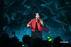 a male in a red jacket is on stage