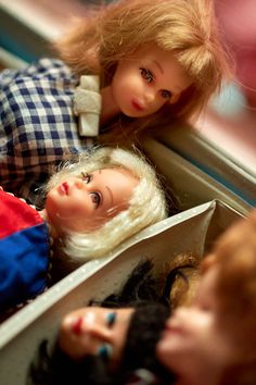 two dolls are sitting in a box on the floor and one is looking at another doll