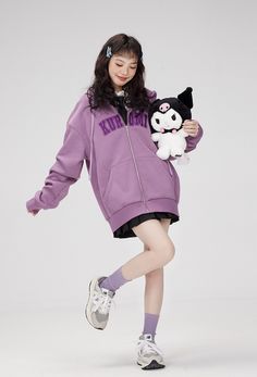 a girl in a purple jacket holding a stuffed animal