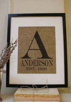 a framed monogrammed burlap with the letter a on it next to some books