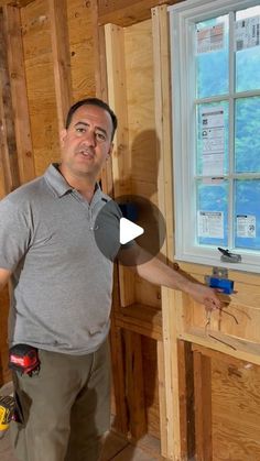 a man standing next to a window in a room under construction