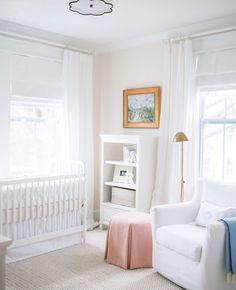 a baby's room with a white crib and pink blanket on the floor