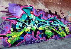 graffiti on the side of a brick building in an alleyway with purple, green and blue spray paint