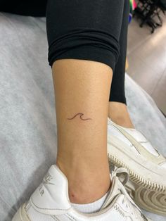 a woman's foot with a small wave tattoo on her left side calfocks