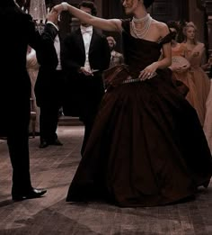 a man in a tuxedo is dancing with a woman in a brown dress