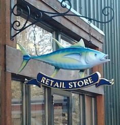 a store sign hanging from the side of a building with a fish painted on it