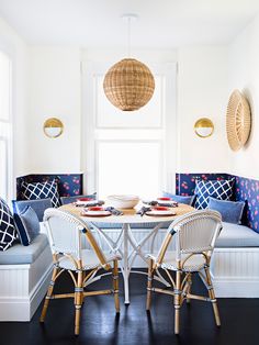 a dining room with white walls and blue cushions on the bench, along with wicker chairs