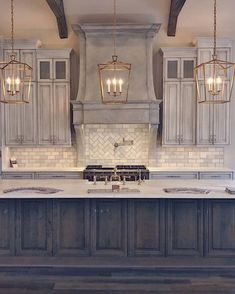 a large kitchen with an island in the middle and two lights hanging from the ceiling