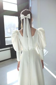 the back of a woman's dress with a white bow at the neckline