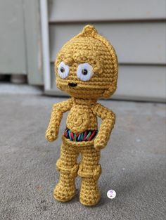 a crocheted toy is standing on the ground next to a garage door with a button in it's mouth