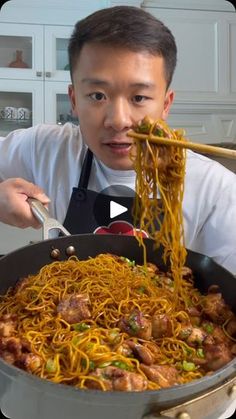 the man is eating noodles with chopsticks in his hand