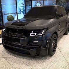 a black range rover is parked in front of a window display at a showroom