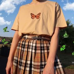 a woman wearing a yellow shirt and checkered skirt with butterflies flying in the background