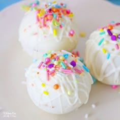 three white cake balls with sprinkles on a plate