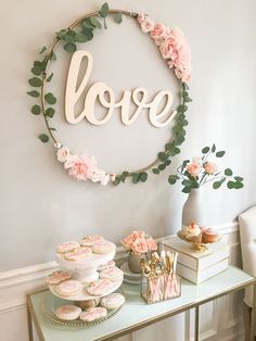 a table topped with cakes and cupcakes next to a sign that says love