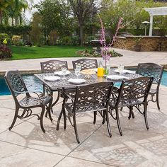 an outdoor dining table and chairs next to a swimming pool