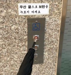 a person with an umbrella is standing in front of a elevator door that has a sign on it