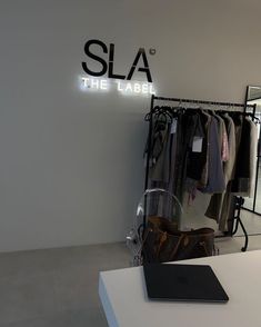 a clothing store with clothes on racks and a laptop sitting on a table in front of it