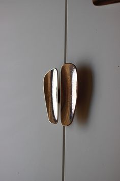 two metal handles on a white door with a handle that has been turned upside down