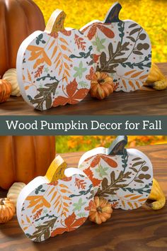 two pumpkins sitting on top of a wooden table next to each other with leaves and acorns painted on them