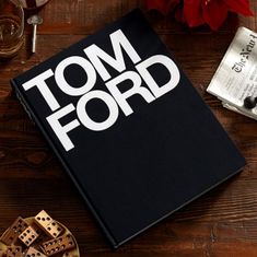 a tom ford book on a wooden table next to some wine glasses and other items