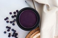 a jar filled with purple liquid next to some blueberries on top of a table