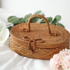 a wicker basket sitting on top of a bed next to flowers