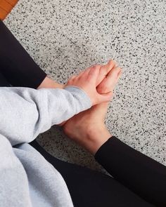 a person sitting on the floor holding their hands together