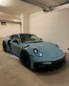 a blue sports car is parked in a parking garage next to a white wall and ceiling