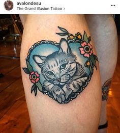 a cat tattoo on the leg of a woman's thigh, with flowers around it