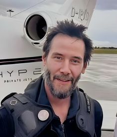 a man in black jacket standing next to an airplane