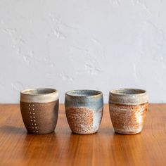 three ceramic cups sitting on top of a wooden table