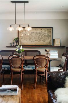 the dining room table is surrounded by brown leather chairs and an old world map on the wall