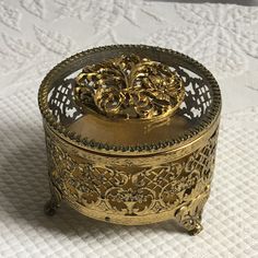 an ornately decorated metal box sitting on top of a white cloth covered tablecloth