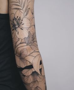 a woman's arm with flowers and leaves on it