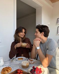 two people sitting at a table with food and drinks