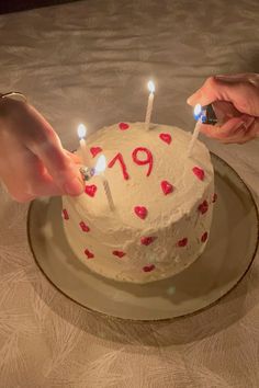 two people lighting candles on a cake with the number 19 written on it and hearts