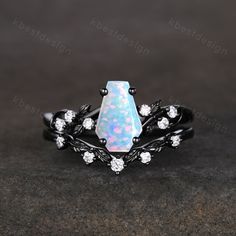 an opalite and diamond ring with leaves on the side, set in black gold