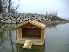 a dog house floating in the water next to some rocks