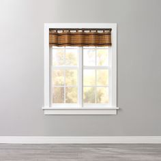 an empty room with a window and wooden floor in front of the window is a white painted wall