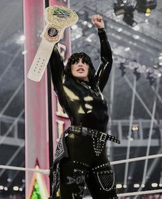 a woman dressed in black holding up a white belted trophy and posing for the camera