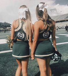 two cheerleaders are standing on the field with their hands in each other's pockets